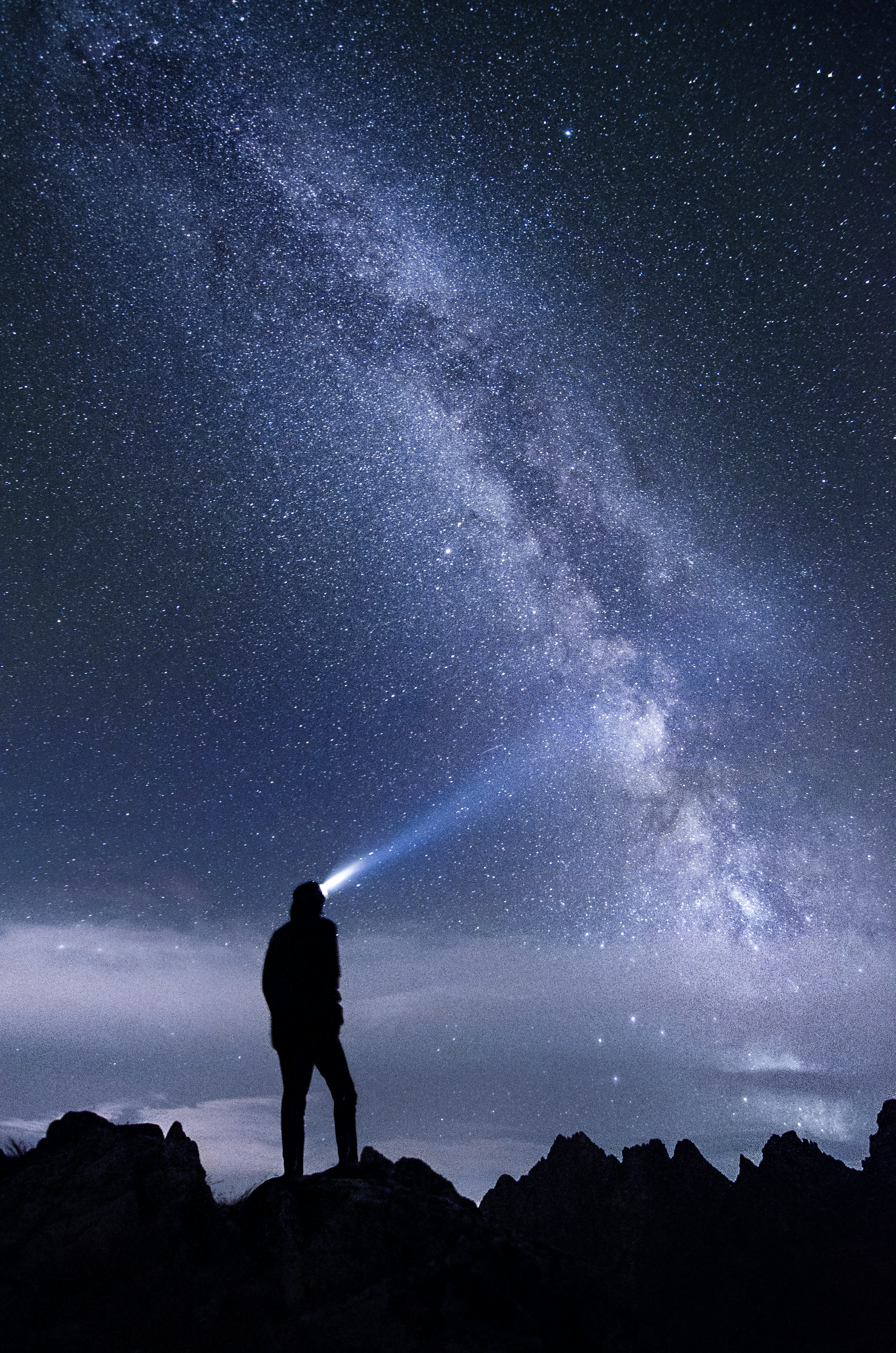 silhouette photo of man using headlamp standing on mountain